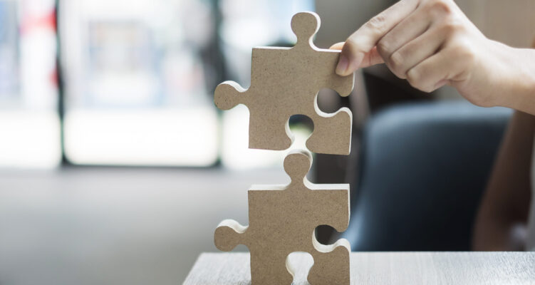 man hands connecting couple puzzle over table, businessman holding wood jigsaw inside office. Business solutions, mission, target, success, goals and strategy concepts